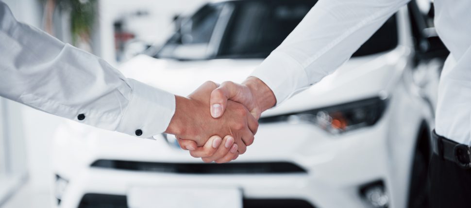 Close up of sales manager in black suit selling the car to the customer